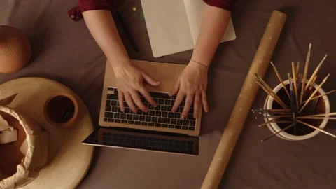 Top-down view of a woman typing on a laptop and writing notes Stock Footage 321313976