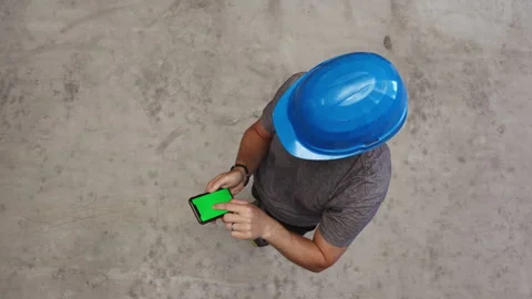 Top down view of a worker wearing a blue hard hat using a smartphone with a.. Stock Footage 339078693