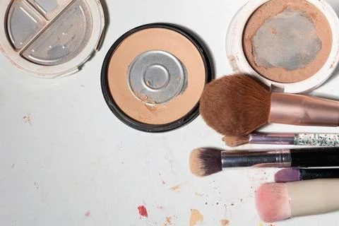 Top-down view of worn powder compacts and dirty brushes, showing powder resid Stock Photos