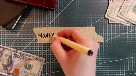 Top down view of writing MONEY MANAGEMENT on tape mockup near dollar bills Stock Footage 338183831