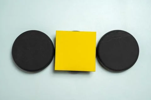 A top-down view of a yellow square tablet positioned between two black circ.. Stock Photos