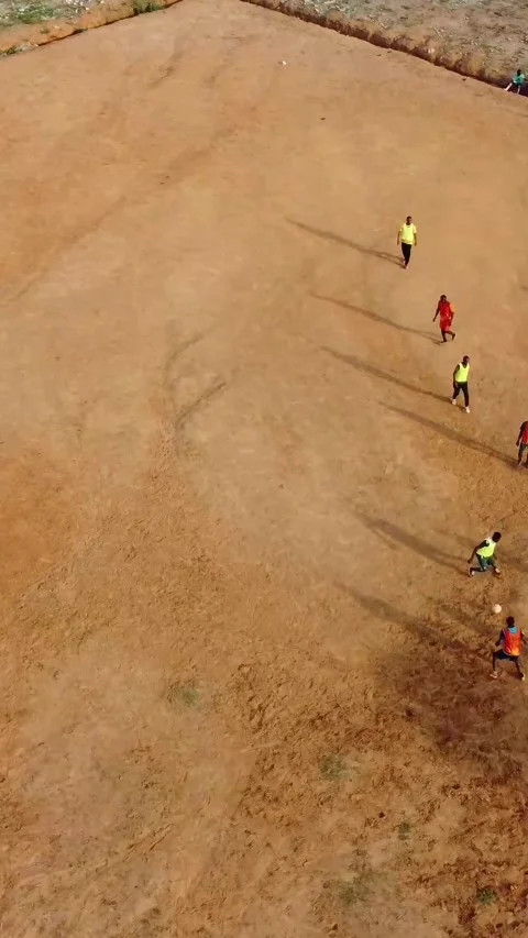 Top-down view of young men playing football on a dirt pitch Video stock 307644669