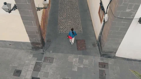 Top down view. A young woman walks along a narrow street of the old town in the Stock Footage 112353825