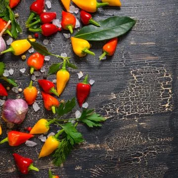 Top down of yellow, red hot chili peppers, sea salt, greenery, black peppers  写真素材