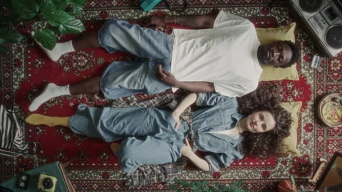 Top Down of Young Couple Resting on Retro Rug Surrounded by 90s Items Stock Footage 339847579
