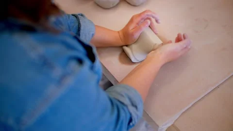 Top down of young woman's hand in pottery studio preparing and rolling clay 库存影片 221949591