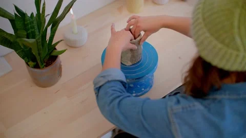 Top down of young woman's hand in pottery studio shaping clay mug on wheel 库存影片 221949634