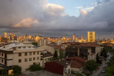 Top drone view of a ctiy under cloudy sky while sun slowly falling down Stock Photos
