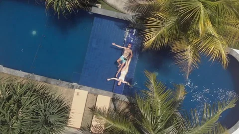 Top drone view of young couple lying up in the swimming pool Stock Footage 128959210