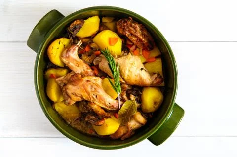 Top flat view of roasted rabbit meat with vegetables in round ceramic pot on Stock Photos