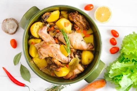 Top flat view of roasted rabbit meat with vegetables in round ceramic pot on  Foto stock