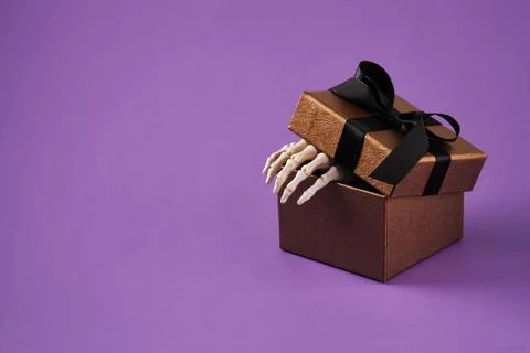 The top of the gift box opens, a skeleton's palm peeks out. Space for your te Stock Photos