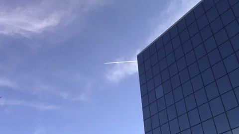 Top of a glass building with a distant plane flying by Stock Footage 70028632