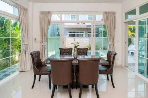 Top granite dining table with dining chairs in spacious room in villa, house  Stock Photos