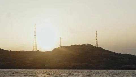 At top of hilly, rocky island, cluster of radio towers is visible, providing Stock Footage 297585196