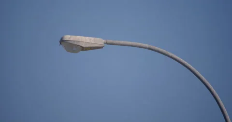 Top of lamp post in wind with seagull passing by in blue sky Stock Footage 130915704