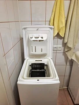 Top-loading washing machine with the open lid stands in the bathroom 库存照片