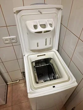 Top-loading washing machine with the open lid stands in the bathroom Stock Photos