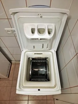 Top-loading washing machine with the open lid stands in the bathroom Stock Photos