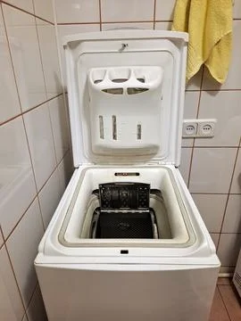 Top-loading washing machine with the open lid stands in the bathroom Фото