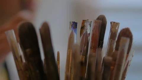 Top of many paint brushes close up with woman painting in background 動画素材 95616259