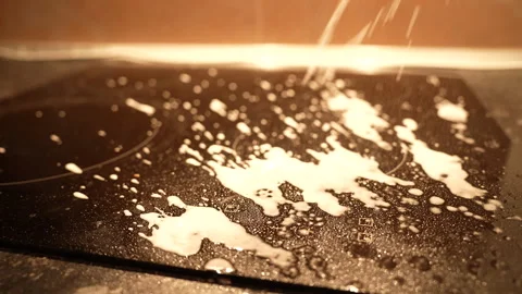 Top medium angle view of black induction stove being cleaned with foaming spray Vídeos de archivo 325802303