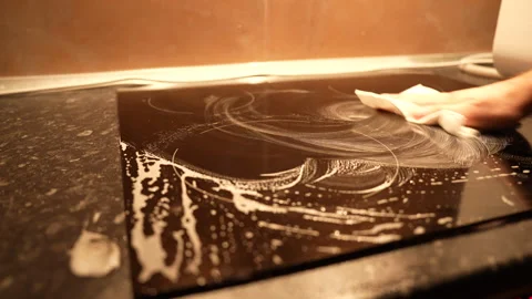 Top medium angle view of black induction stove being cleaned with foaming spray Stock Footage 325802344