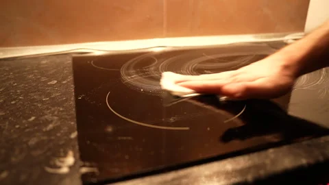 Top medium angle view of black induction stove being cleaned with foaming spray Stock Footage 325802359