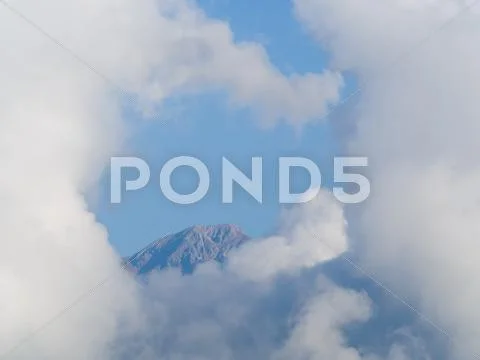 Top of a mountain completely surrounded by white heavenly clouds Stock Photos