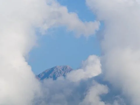 Top of a mountain completely surrounded by white heavenly clouds Stock Photos