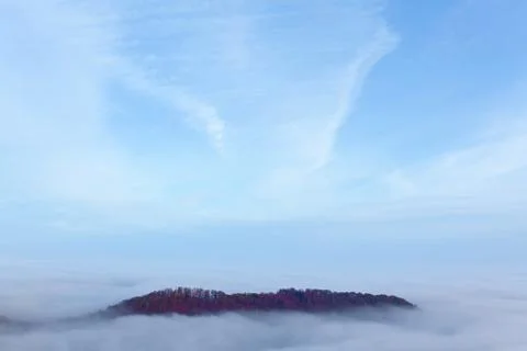Top of a mountain peaking from low clouds and thick fog, with blue sky Foto stock