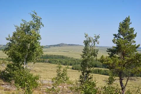 The top of a mountain range against the background of fields and forests Stock Photos