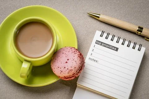 Top priorities, notes in a small spiral notebook or calendar with a cup of .. Stock Photos