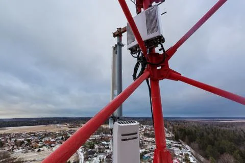 Top of red telecommunication tower with vertical panel antenna and remote radio Stock Photos