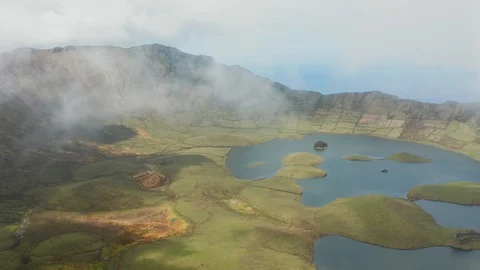 Top of ridge in clouds. Green fields and lake at the foot of a mountain. Aerial Video stock 119891950