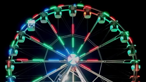 Top section of amusement ride glowing with white and blue lights on black Stock Footage 330742346