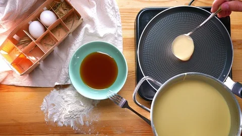 Top shot, appetizing pancake is being cooked with frying pan on wooden table Video stock 96484224
