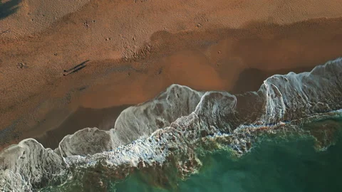 Top shot of a beach line, white waves, blue sea and two people walking Stock Footage 223333501
