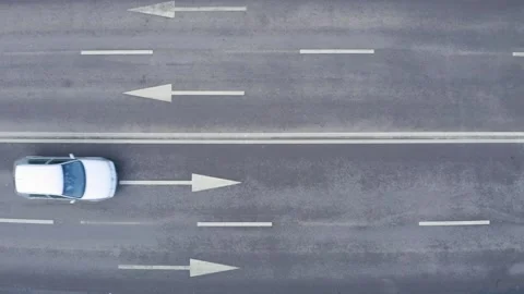 Top shot in the loop of two cars in traffic. Four lane road marked with arrows. Stock Footage 150610732