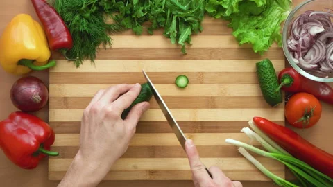 Top shot of man chef cutting cucumber on chopping wooden board Stock Footage 87813293