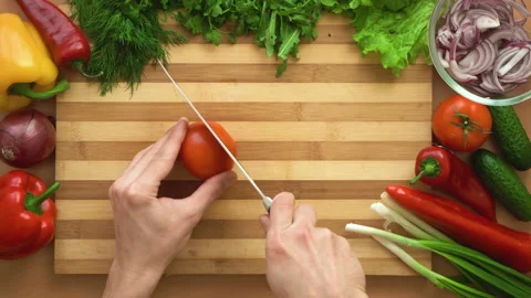 Top shot of man chef cutting tomatoes on chopping wooden board Stock Footage 87902332