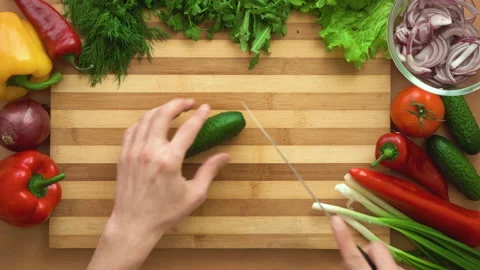 Top shot of man chef cutting cucumber on chopping wooden board Stock Footage 87902949