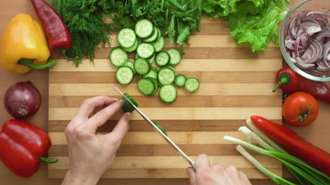 Top shot of man chef cutting cucumber on chopping wooden board Stock Footage 88000011