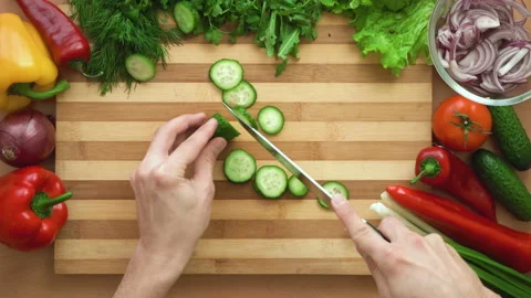 Top shot of man chef cutting cucumber on chopping wooden board Stock Footage 88166529