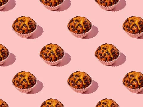 Top shot seamless pattern of a yummy chocolate chips cupcake on a pink backgr Stock Photos
