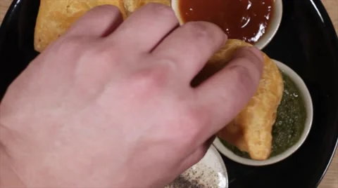Top-shot track-in close-up of a hand grabbing a Samosa from a plate Vídeo Stock 62922997