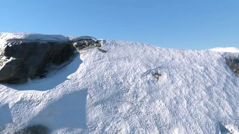 The top of a snow-capped mountain floats smoothly in front of the camera against Stock Footage 148383503