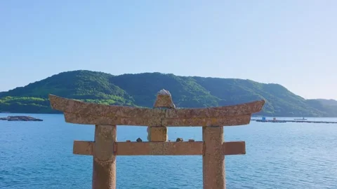 Top structure of Torii gate with calm blue ocean and mountain in background Stock Footage 340749811