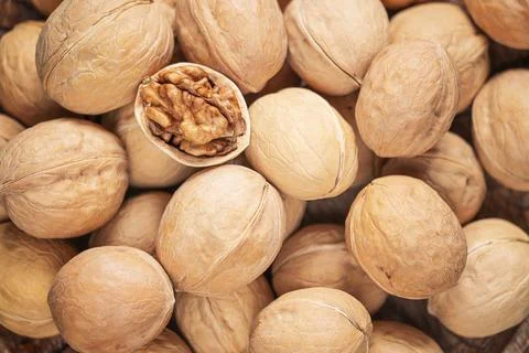 Top table view of background with whole and cracked walnuts in shell. Stock Photos