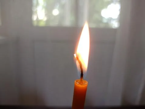 The top of a thin wax monastic candle with a bright flame Stock Photos